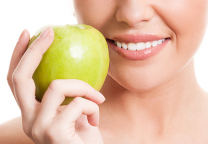 closeup of the face of a woman holding a green apple, isolated against white background